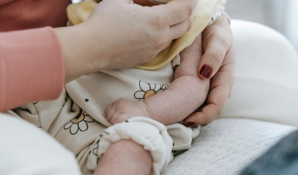 crop unrecognizable woman feeding baby from bottle