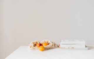 cotton sack with sweet apricots placed on table with textbooks