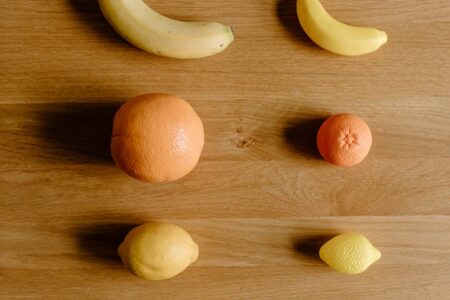 citruses and bananas placed on wooden surface